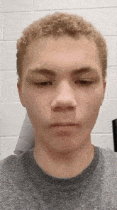 a close up of a young man 's face with a gray shirt on .
