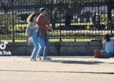 a man and a woman are walking down a sidewalk next to a man sitting on the sidewalk