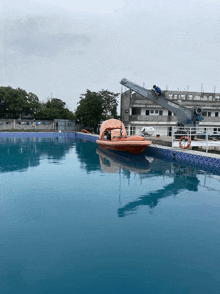a boat is floating in a swimming pool with a crane nearby