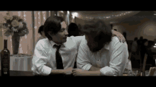 two men in white shirts and ties are hugging