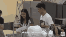 a man and a woman are standing in a kitchen washing dishes .