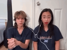 a girl wearing a scotland t-shirt is sitting next to another girl
