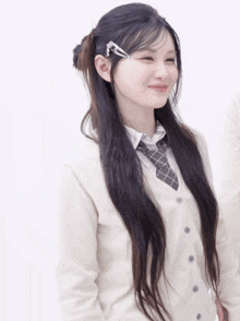 a girl with long black hair wearing a white cardigan and tie