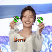 a woman in a white sweater is holding up two green stickers and the word mone is on the bottom