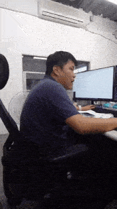 a man is sitting at a desk in front of a computer screen