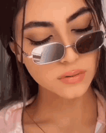 a close up of a woman wearing sunglasses and a pink shirt