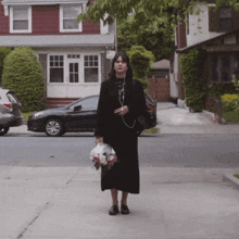 a woman in a black dress holding a bag of flowers
