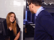 a man and a woman are standing next to each other and talking to each other .