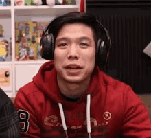 a man wearing headphones is wearing a red hoodie with the number 8 on it