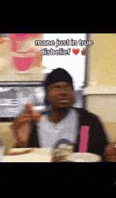a blurry picture of a man sitting at a table with the words mane just in true disbelief above him