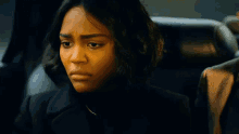 a woman in a black coat is sitting in the back seat of a car and making a funny face .