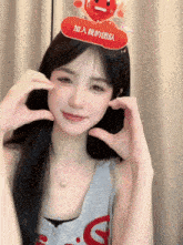 a woman wearing a headband that says ' 加入 我 的 团队 ' is making a heart with her hands