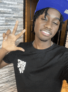 a young man wearing a blue hat and a black shirt that says thug guys 90