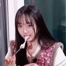 a young girl with long hair is eating something with a fork .