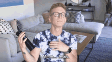 a man in a tie dye shirt is holding a bottle and says jesus