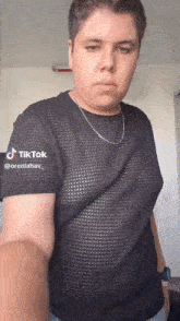 a young man wearing a black shirt and a silver chain has a tiktok account