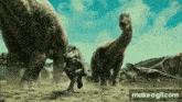 a group of dinosaurs are standing in the dirt near a make a gif.com advertisement
