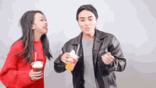 a man and a woman are standing next to each other and holding drinks .