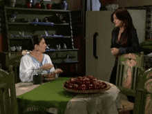 two women sit at a table with a plate of apples