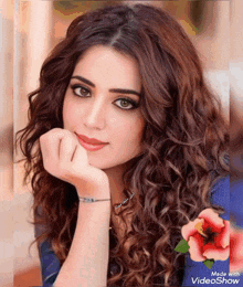 a woman with curly hair has her hand on her chin