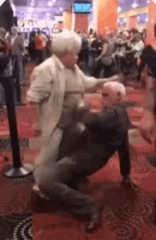 a man and a woman are fighting in a crowded room in a casino .