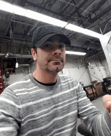 a man wearing a hat and a striped shirt is taking a selfie