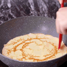 a person is cooking a crepe in a pan with a spatula