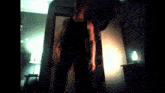 a man in a black tank top is standing in front of a door