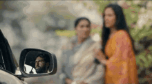 a man is driving a car and looking at his reflection in the side mirror .