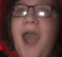 a close up of a person 's face with glasses and a red background .