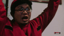 a man wearing glasses and a red shirt has his arms in the air and the word bull is on the bottom