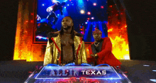 a man in a gold robe is standing next to a man in a red suit on a stage .