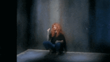 a woman with red hair is sitting on the floor with her hands on her face