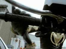 a person is riding a motorcycle with a black glove on the handlebars