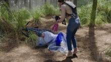 a person is laying on the ground in the woods with a bicycle in the background