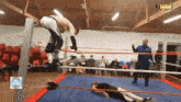 a wrestler is jumping over another wrestler in a wrestling ring with a sign that says ashley on it
