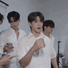 a group of young men in white shirts are standing in a room