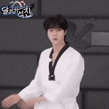 a man in a taekwondo uniform is standing in front of a wall with korean writing on it