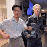 a couple of men are standing next to each other in a room and dancing .