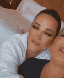 two women are laying next to each other on a bed and looking at each other .