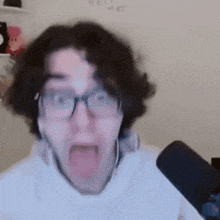 a man with glasses is making a funny face in front of a microphone