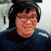 a man wearing glasses and headphones is smiling while wearing a blue shirt .
