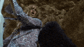 a woman in a leopard print shirt screams while laying on the ground