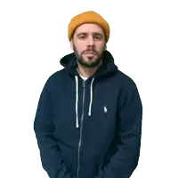 a man with a beard wearing a blue hoodie and yellow hat