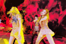 a group of women are dancing on a stage in front of a fire background