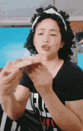 a woman with curly hair is eating a piece of food