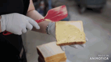 a person is spreading butter on a slice of bread with a spatula made in animatica