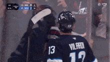 a hockey player wearing a number 13 jersey talks to another player
