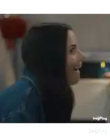 a woman in a denim jacket is laughing with her mouth wide open