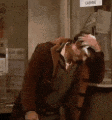 a man is scratching his head while sitting at a counter in a store .